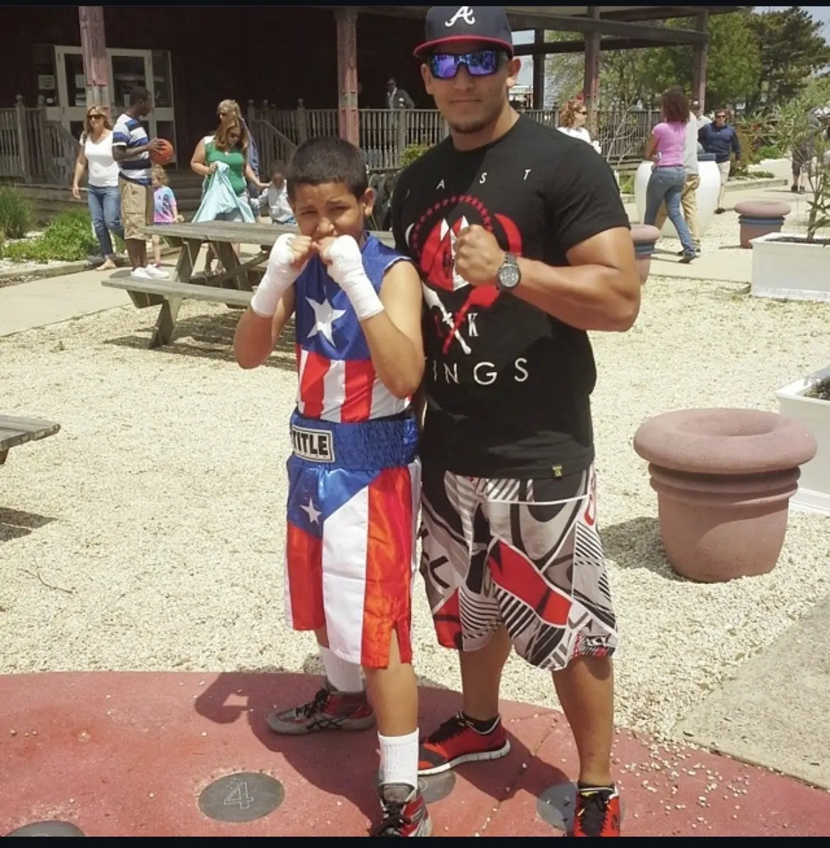 Christian Figueroa at age 12 wearing a Puerto Rican boxing uniform beside an adult boxer